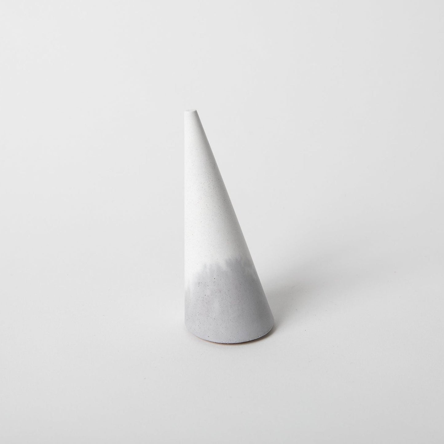 Cone shaped concrete ring holder with cork base in grey and white.