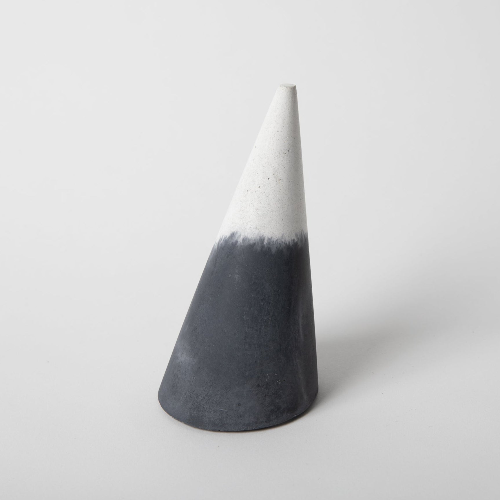 Cone shaped concrete bangle holder with cork base in black and white.